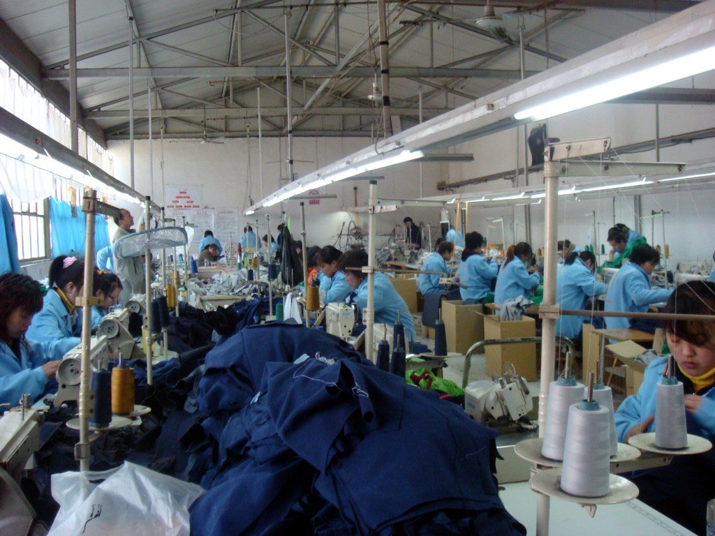缝纫车间多名穿蓝工服工人缝纫机前作业