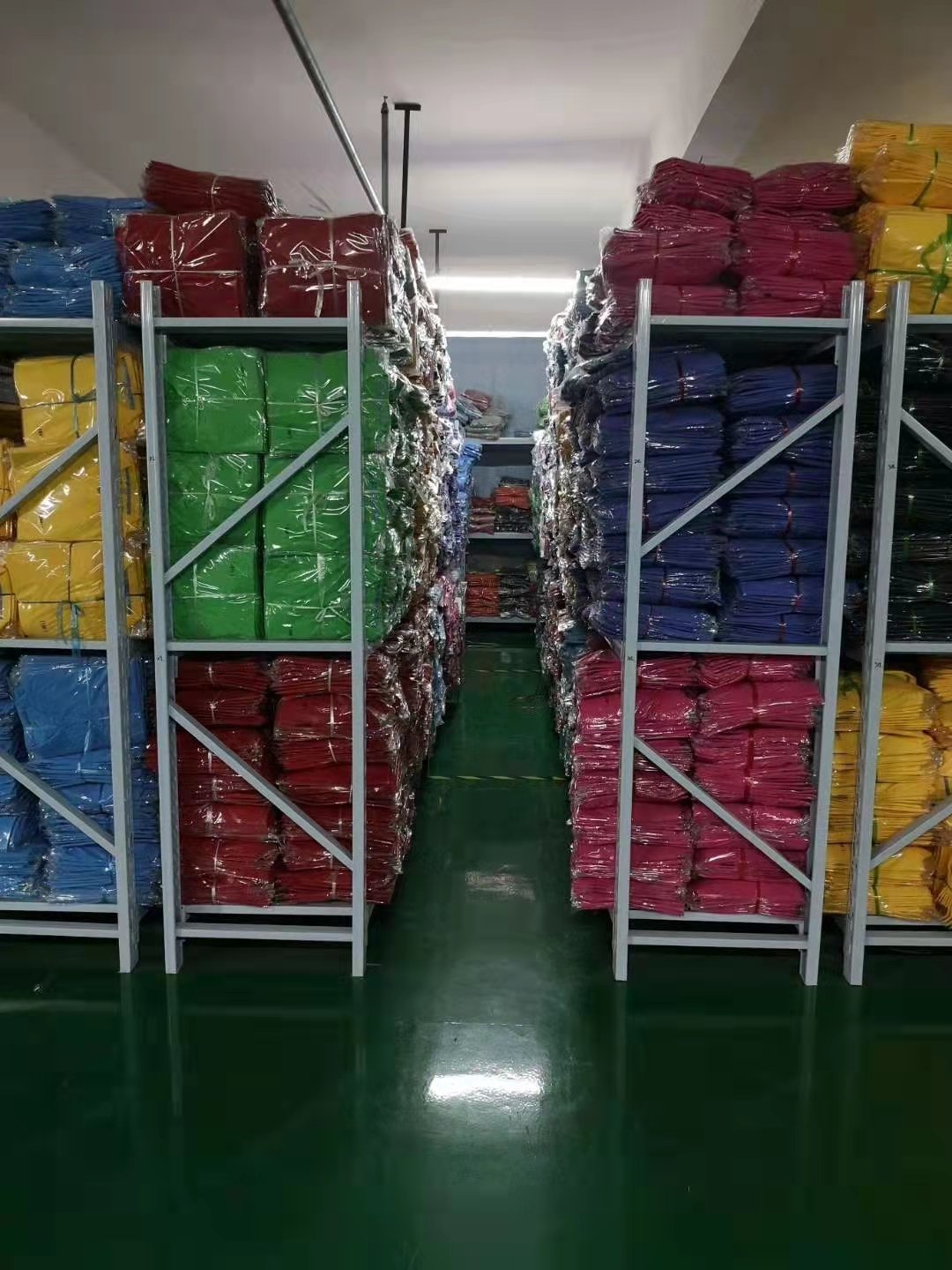 成品仓库货架整齐堆叠各色成包T恤存货