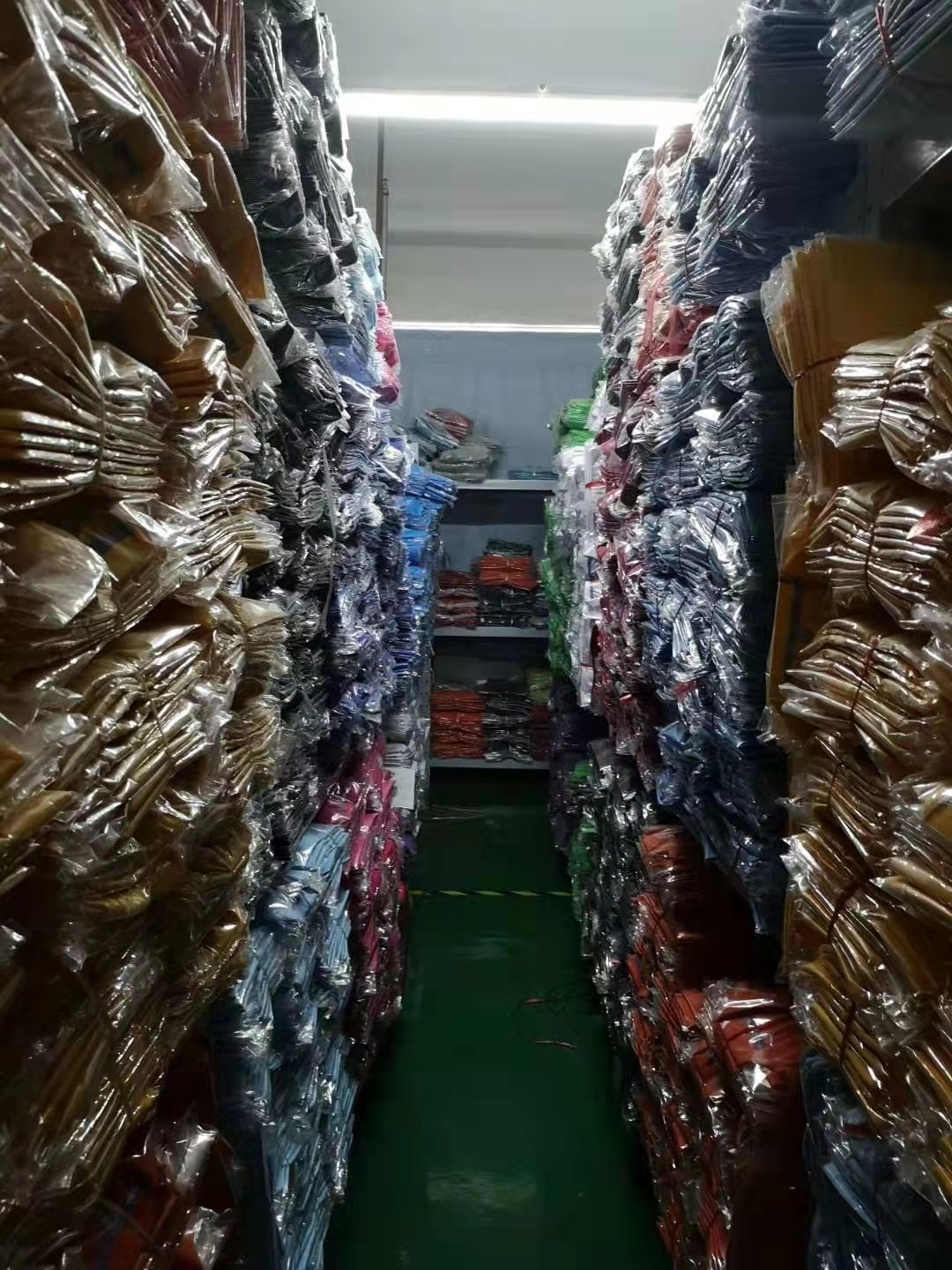 仓库通道两侧高货架堆满包装成衣——备货充足的仓库